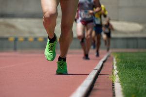 Close-up picture of four people's legs running single file on a track.