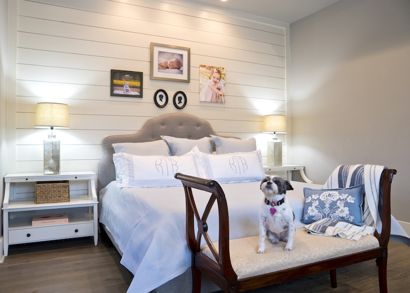 A shiplap wall in the master bedroom brings farmhouse tranquility to the private quarters where photography and children’s silhouettes are displayed. Hand embroidered linens and bedding from Lin Marché. One of the three family dogs, Little Molly, holds court on a bench that once belonged to Katherine’s mother.